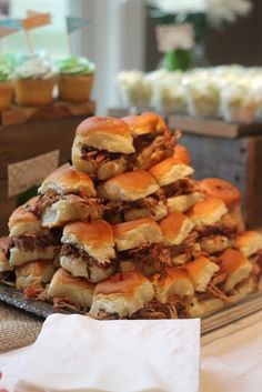 a pile of sandwiches sitting on top of a table next to cupcakes and cake