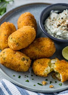 some food is on a plate with a small bowl of sauce and a lime slice