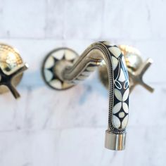 two bathroom faucets on the wall with white and black designs painted on them