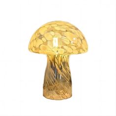 a yellow glass mushroom shaped lamp on a white background with lots of gold coins in it