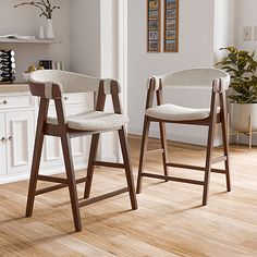 two stools in the middle of a kitchen with wood floors and white walls, one is