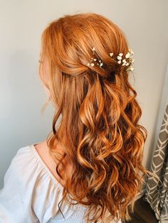 a woman with long red hair and flowers in her hair is looking at the mirror