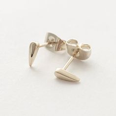 Tiny stud earrings in the shape of a tusk. The perfect, just barely there, everyday earring in a fun shape. Length: 3.5 mm. Our materials make for an amazing, high quality, seamless, jewelry piece with longevity. Our earrings are plated with 18k gold, 18k rose gold, or rhodium and finished with a protective coating. A little secret we’ll keep between us: it looks way more than it costs. Triangle Earrings Stud, Stud Earrings Silver, Stud Earrings Gold, Triangle Studs, Link Earrings, Circle Earrings Studs, Tiny Studs, Between Us, Tiny Stud Earrings