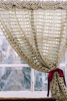 a curtain with a red bow hanging from it's side in front of a window