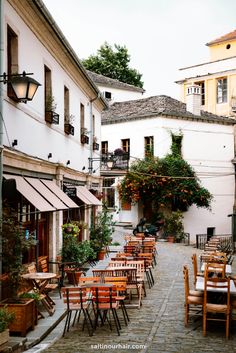 an alley way with tables and chairs lined up along the side of each other in front of buildings