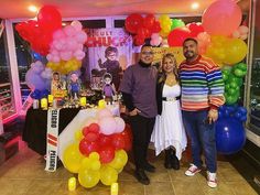 two men and a woman standing in front of a cake table with balloons on it