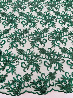 the green and white lace is on top of a tablecloth with floral designs in it