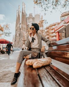 a person sitting on a bench talking on a cell phone and holding a baguette