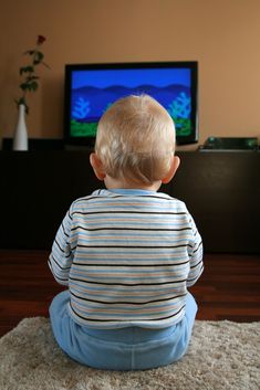 a little boy sitting on the floor in front of a tv