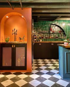 an orange and black checkered floor in a bar with green tiles on the walls