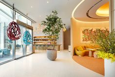 a large room with lots of windows and plants in the center, along with colorful artwork on the walls