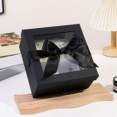 a black box with a bow sitting on top of a table next to a camera