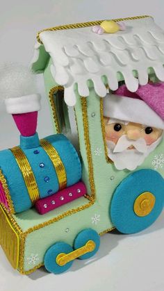 a small toy train with santa clause on it's head and blue, green, pink and yellow wheels