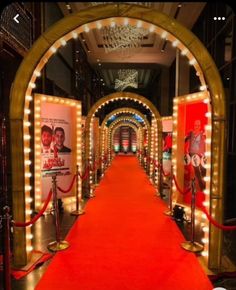 a red carpeted hallway with lights and posters on the walls, leading to an entrance