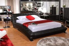 a bedroom with black and white furniture and red pillows on the bed, along with mirrored walls