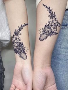 two people with matching tattoos on their arms holding each other's hands and flowers