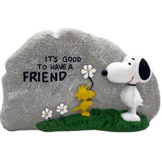 a statue of a snoopy dog with flowers on it's head and the words, it's good to have a friend