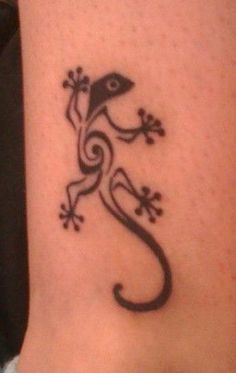 a small lizard tattoo on the side of a woman's leg, it is black and white