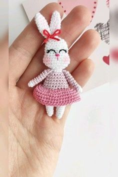 a small crocheted bunny doll in a pink dress is held by someone's hand