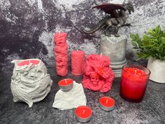 some candles are sitting on a table next to a dragon statue and vases with flowers in them