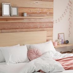 a bed with white sheets and pink pillows