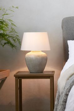 a white lamp sitting on top of a table next to a bed