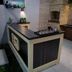 an outdoor bar with wine glasses on it and a television mounted to the wall behind it