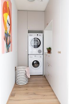 a washer and dryer are in the corner of this small room with wood flooring