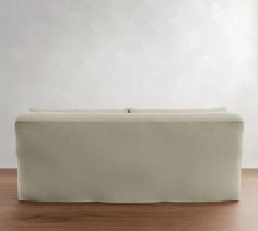 a couch sitting on top of a wooden floor next to a white wall and window