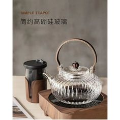 a glass teapot sitting on top of a wooden tray