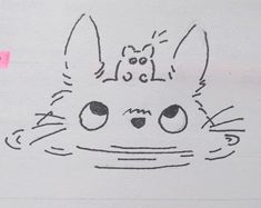 a drawing of a cat's face with eyes and ears drawn on paper next to a piece of pink tape