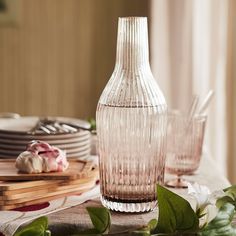 a glass vase sitting on top of a table next to plates and utensils