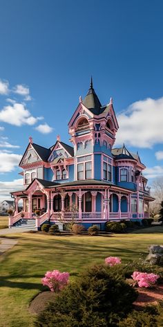 a large pink and blue house sitting on top of a lush green field