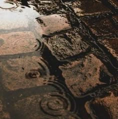 the reflection of an umbrella and its reflection in a puddle on the ground with cobblestone pavement