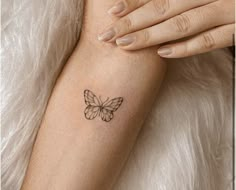 a woman's arm with a small butterfly tattoo on the left side of her arm