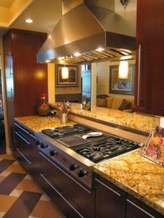 a kitchen with granite counter tops and stainless steel oven hoods, along with a checkered floor