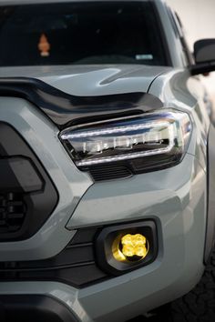 the front end of a silver truck with yellow lights