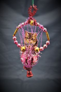 a cat ornament hanging from a string with beads and other things on it