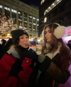 two women standing in front of christmas lights