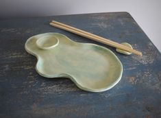 two chopsticks and a plate on top of a wooden table with blue paint