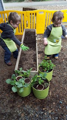 two children in aprons and green aprons planting plants