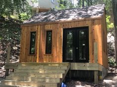 a tiny house built in the woods with steps leading up to it's front door