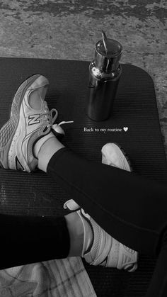 black and white photograph of woman's feet on exercise mat with coffee cup in background