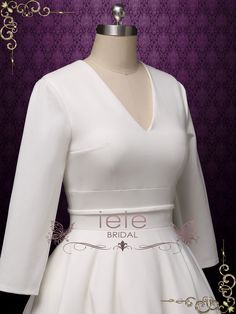 a white wedding dress on a mannequin headdress with purple wallpaper in the background