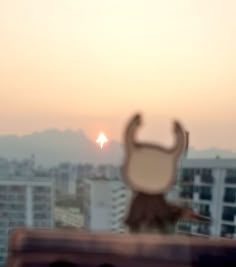 a blurry photo of the sun setting over a city with buildings in the background