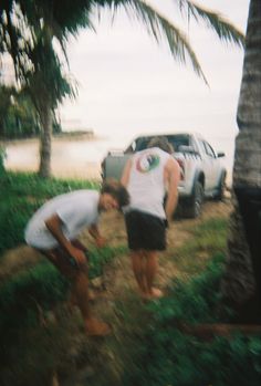 two men are bending over to pick up something off the ground