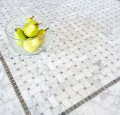 a bowl filled with pears on top of a tiled floor