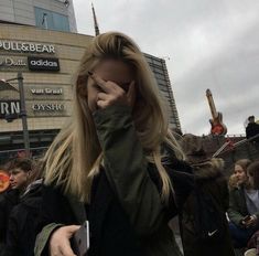 a woman is standing in front of a building talking on her cell phone and holding her hand up to her face