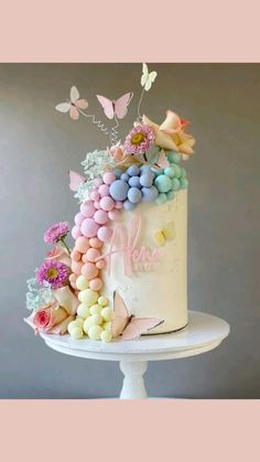 a white cake topped with lots of colorful candies and butterflies on top of it