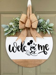 a welcome sign hanging on the front door with a bow around it's neck